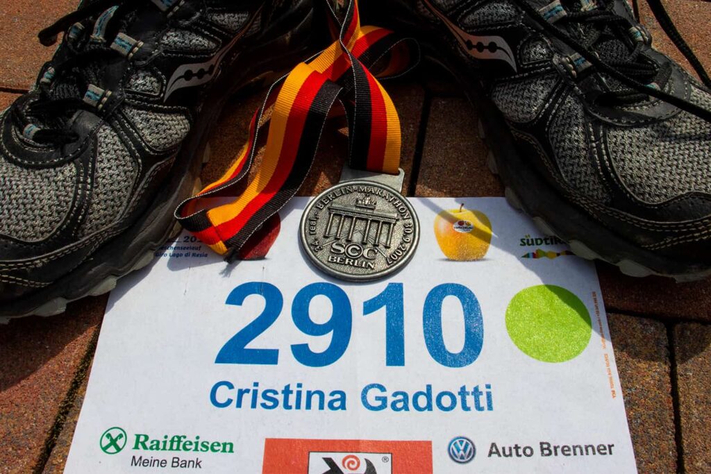 Gros plan sur la médaille, le dossard et les chaussures Running de Cristina Gadotti