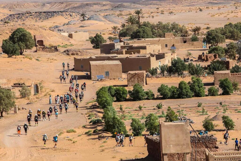 Les coureurs traversent un petit village du Sahara lors du MDS, une véritable course running de survie.