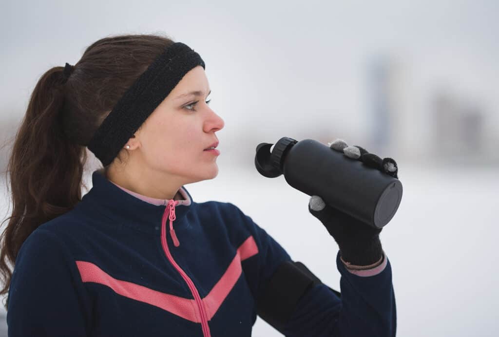 femme avec bandeau et gourde qui fait une pause lors de sa session