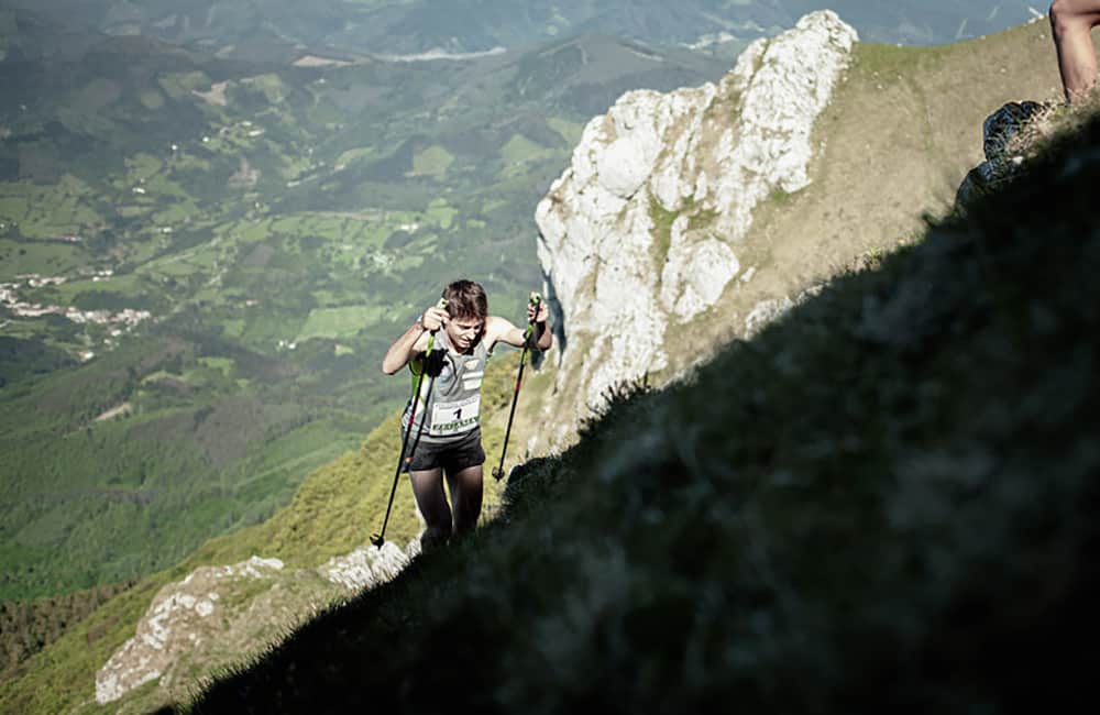 coureur de trail grimpant une colline raide avec les prairies en arrière-plan