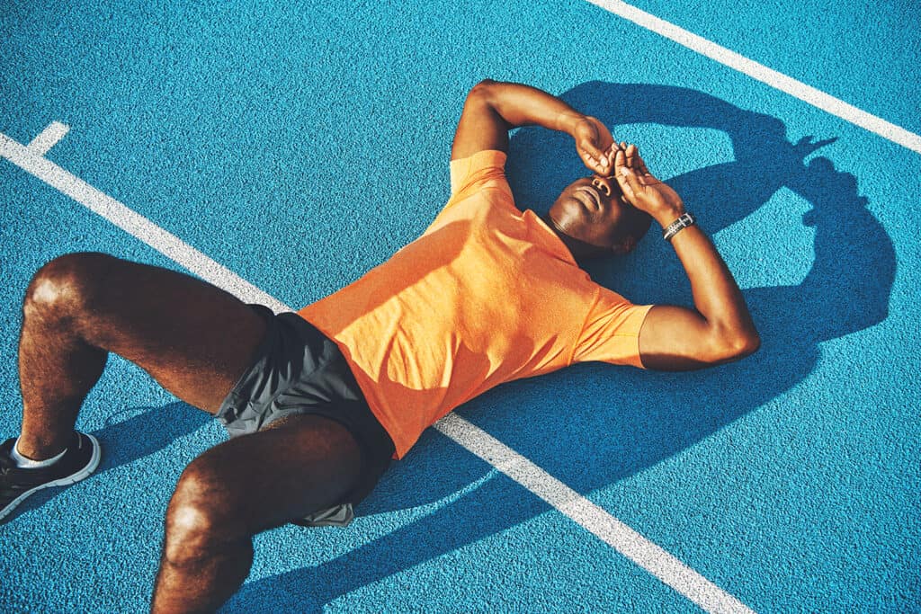 coureur fatigué allongé sur une piste pour récupérer après une course
