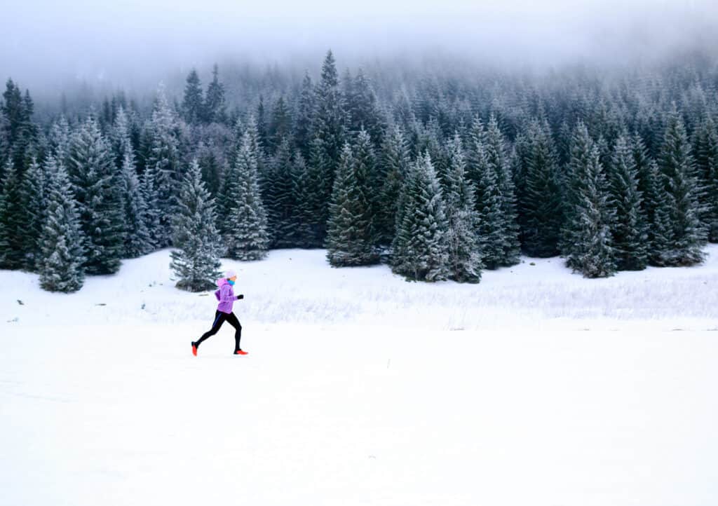 Coureuse sur neige compacte l'hiver en forêt (sa chaussure a un crampon)