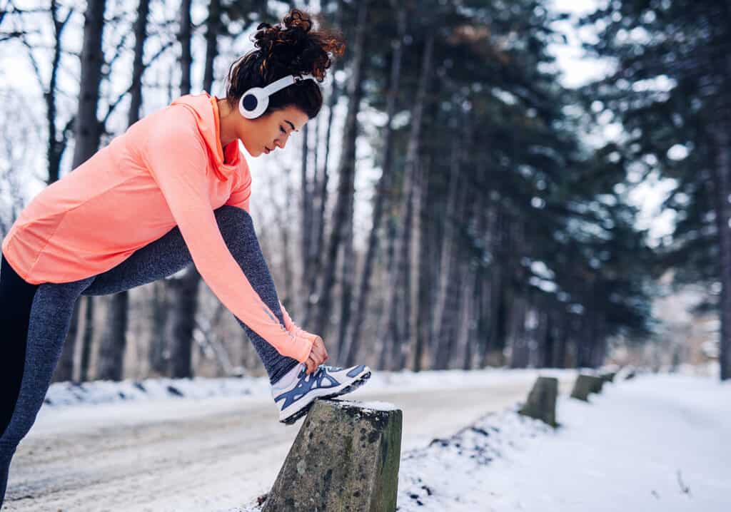 Jeune femme laçant ses chaussures en plein air