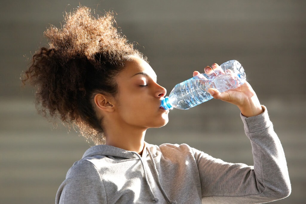 Femme buvant de l'eau avant le sport pour éviter la crampe