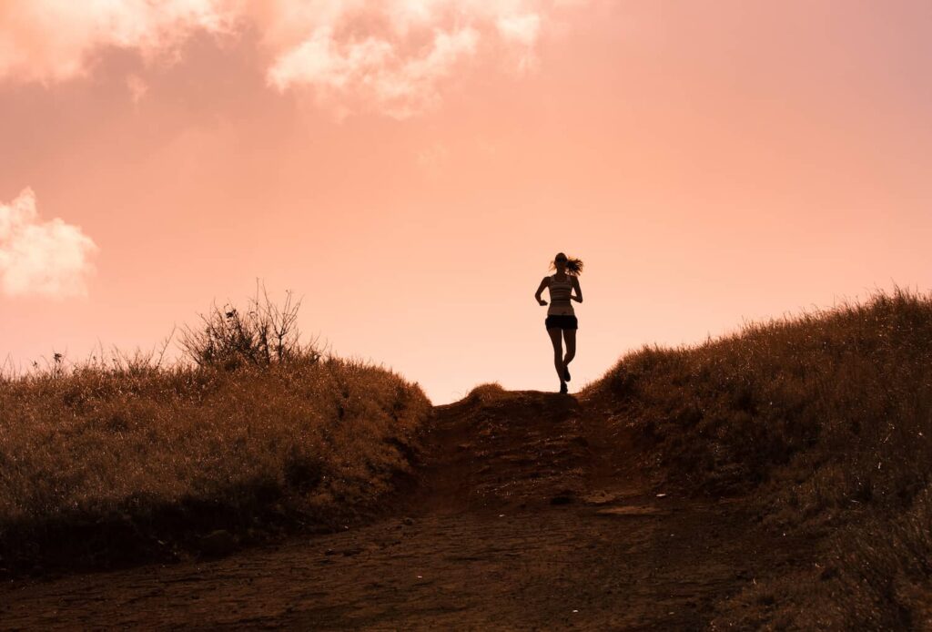 femme qui court sur un sentier au coucher du soleil