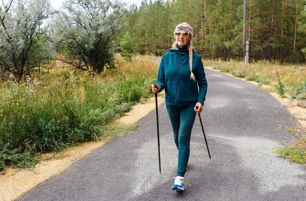 marche nordique dans la nature (un des sports de marche). Un bâton est en arrière, l'autre bâton est devant la personne.