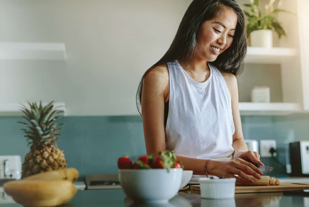 Femme-préparant-salade-santé-à-partir-de-fruits-frais-dans-la-cuisine