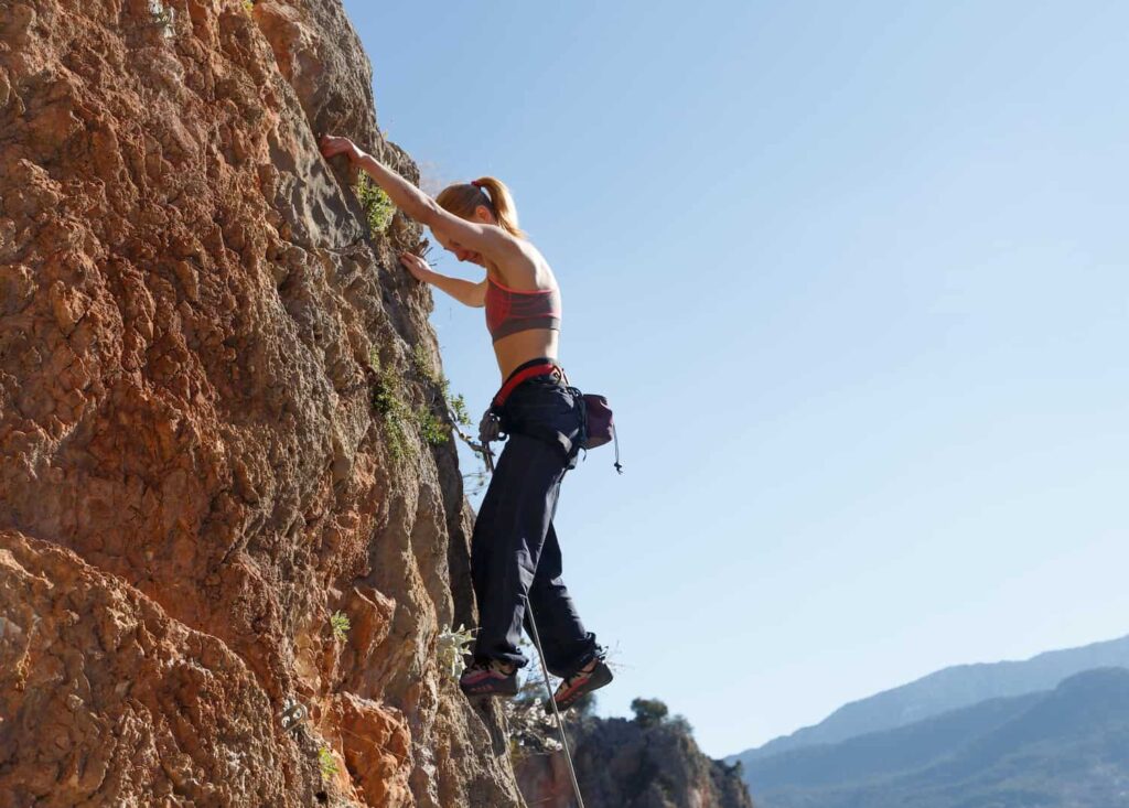 femme qui escalade une route avec une équipement d'approche et d'escalade