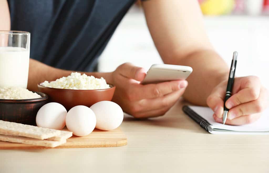 Homme comptant les calories sur une table avec de la nourriture riche en apports et acide aminé