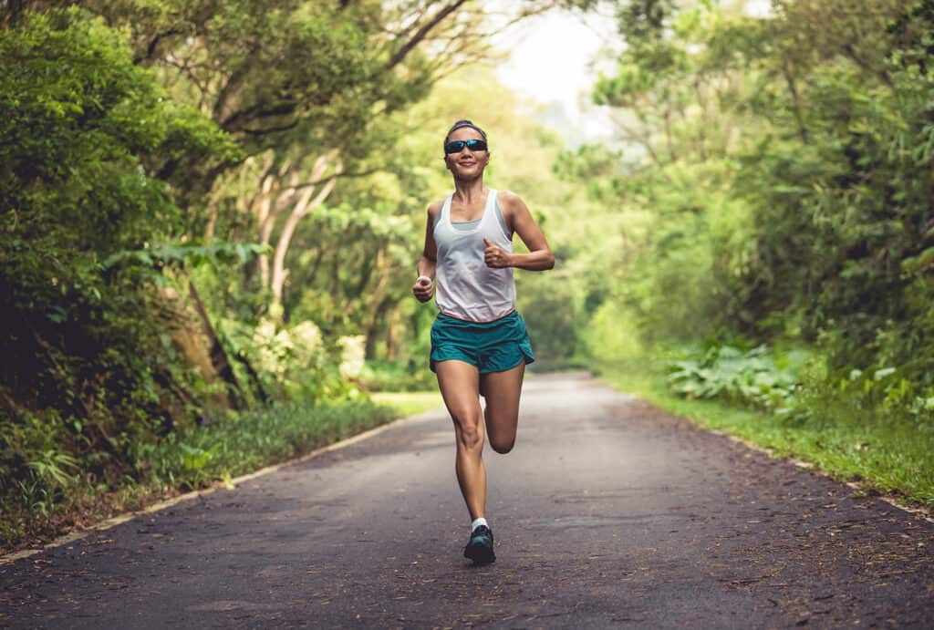 Femme courant sur le sentier d'un parc d'été