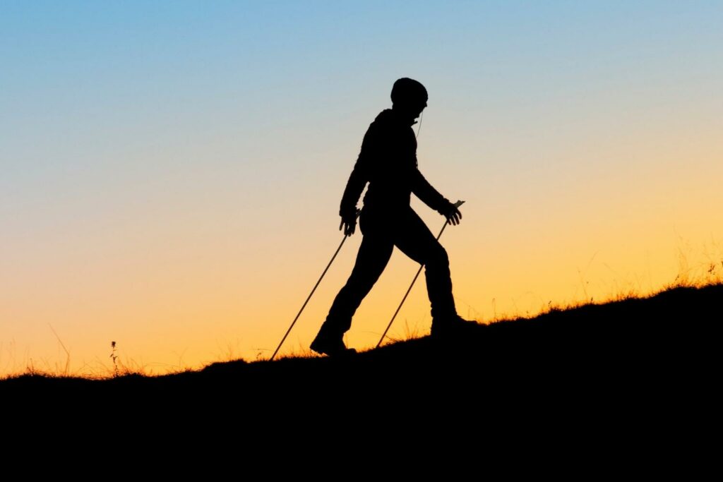 marcheur qui pratique le sport en plein air au coucher du soleil. La position de la jambe droite est en avant.