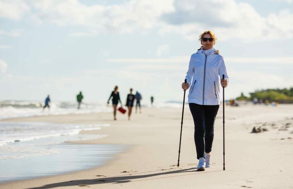 randonneuse nordique sur la plage qui fait travailler le haut du corps