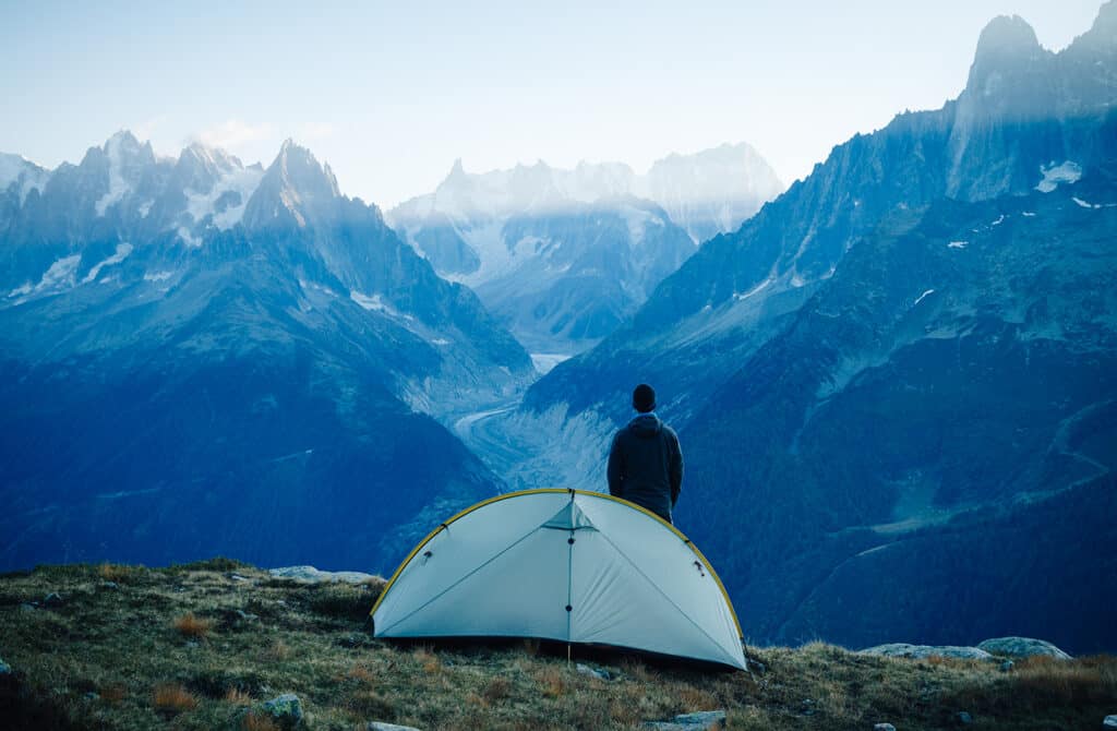 Un randonneur se tenant près de sa tente et regardant les montagnes. Mont Blanc, Chamonix