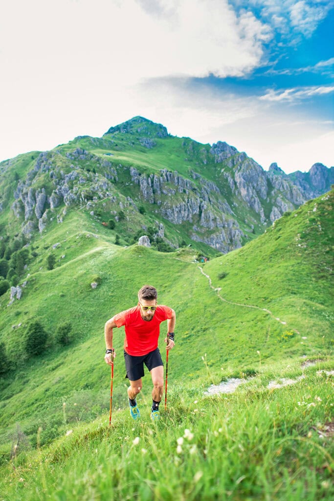 homme escaladant un sentier de montagne escarpé à l'aide de bâtons
