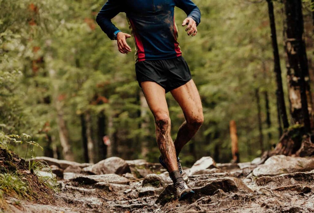 homme qui court sur un chemin boueux avec des racines