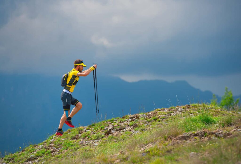 trail runner avec bâtons en montagne