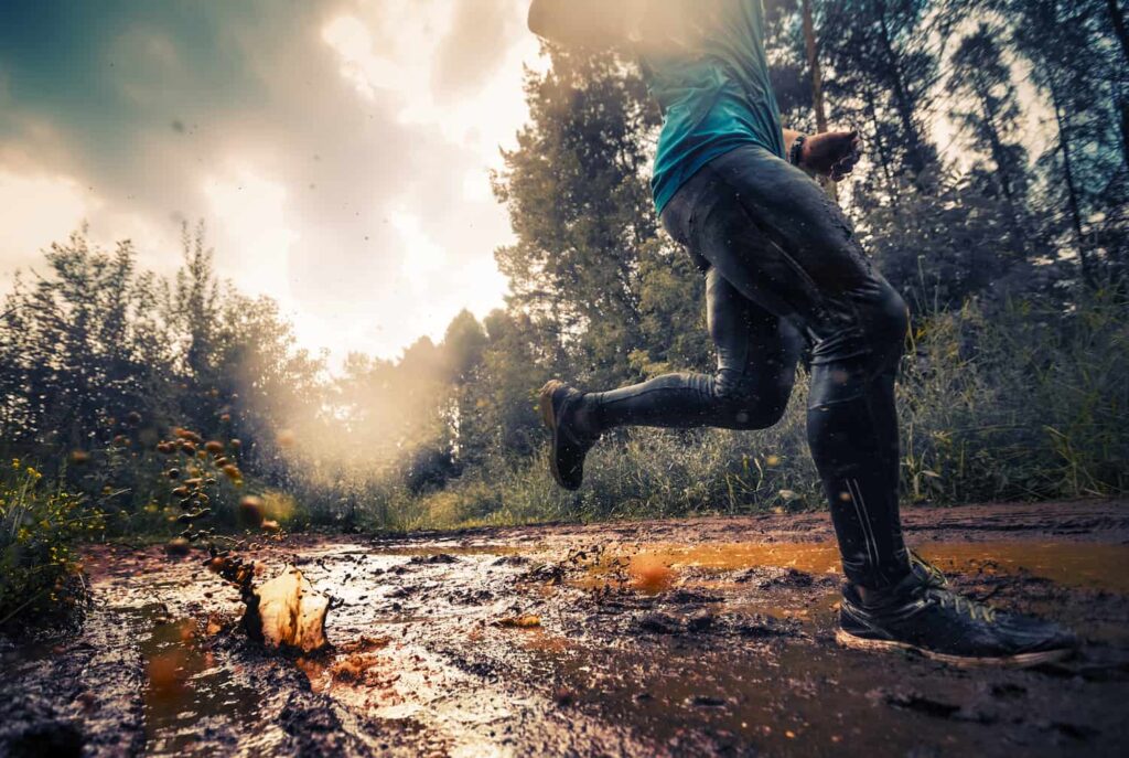 homme qui met à l'épreuve sa chaussure de trail dans une flaque d'eau