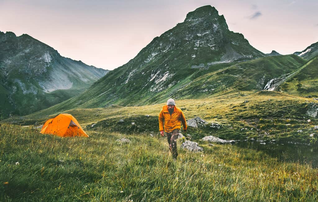 Man hiking alone with tent in mountains